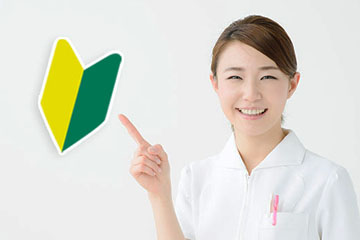 初めての方へ（若葉マークを指さす歯科スタッフ）