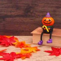 ハロウィンのかぼちゃの人形と紅葉の落ち葉、秋の季節感を表す写真
