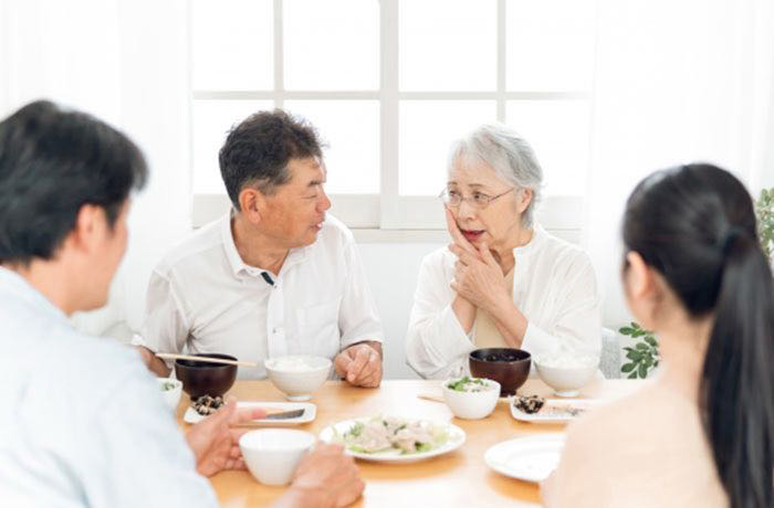 敬老の日に家族で食事をしながら高齢者の入れ歯やお口の状態を確認する様子