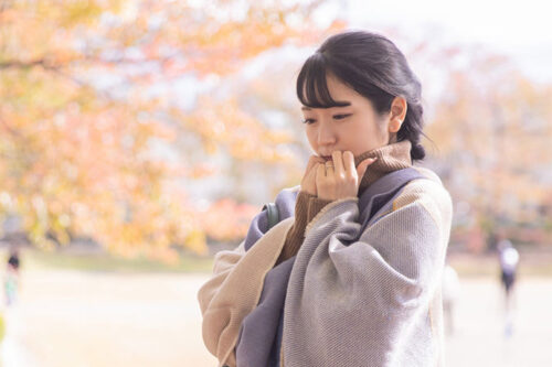 寒さに身をすくめる女性―寒い季節に気をつけたい歯の食いしばりと対策